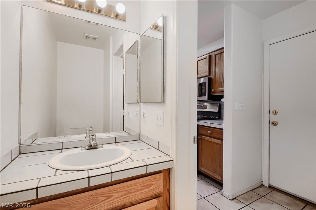 A tiled vanity top integrates with the adjacent hallway and kitchen spaces.
