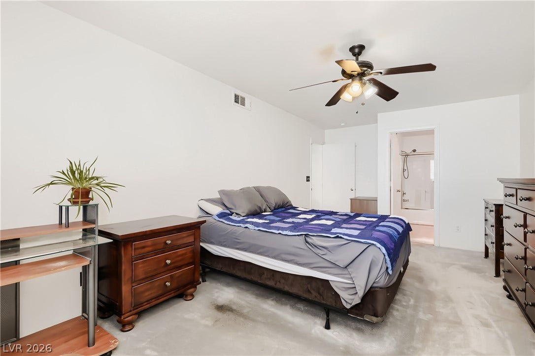 Smooth concrete flooring and an attached bathroom define this modern bedroom space.
