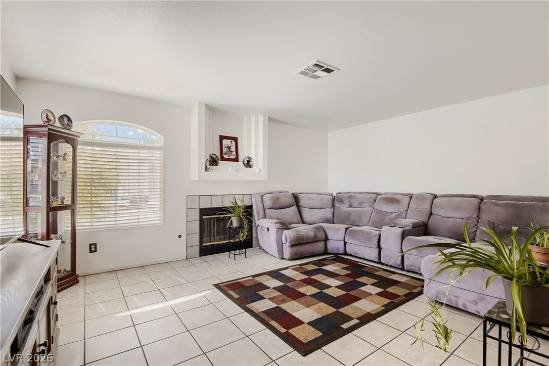 An arched window and tiled fireplace add classic architectural detail to this airy living space.