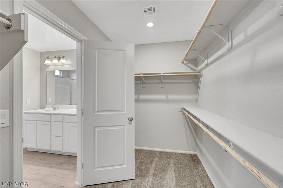 Primary Bedroom Walk-In Closet provides ample built-in shelving and hanging rods for better organization.