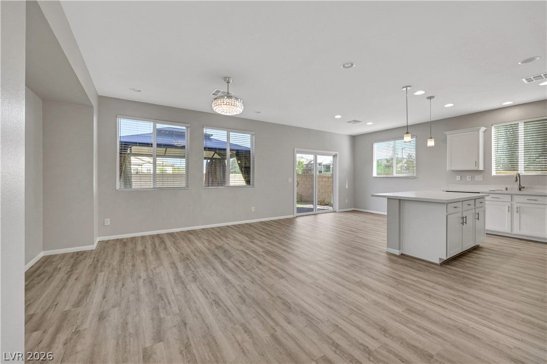 Luxury vinyl plank flooring runs throughout a spacious, open-concept living area and modern kitchen.