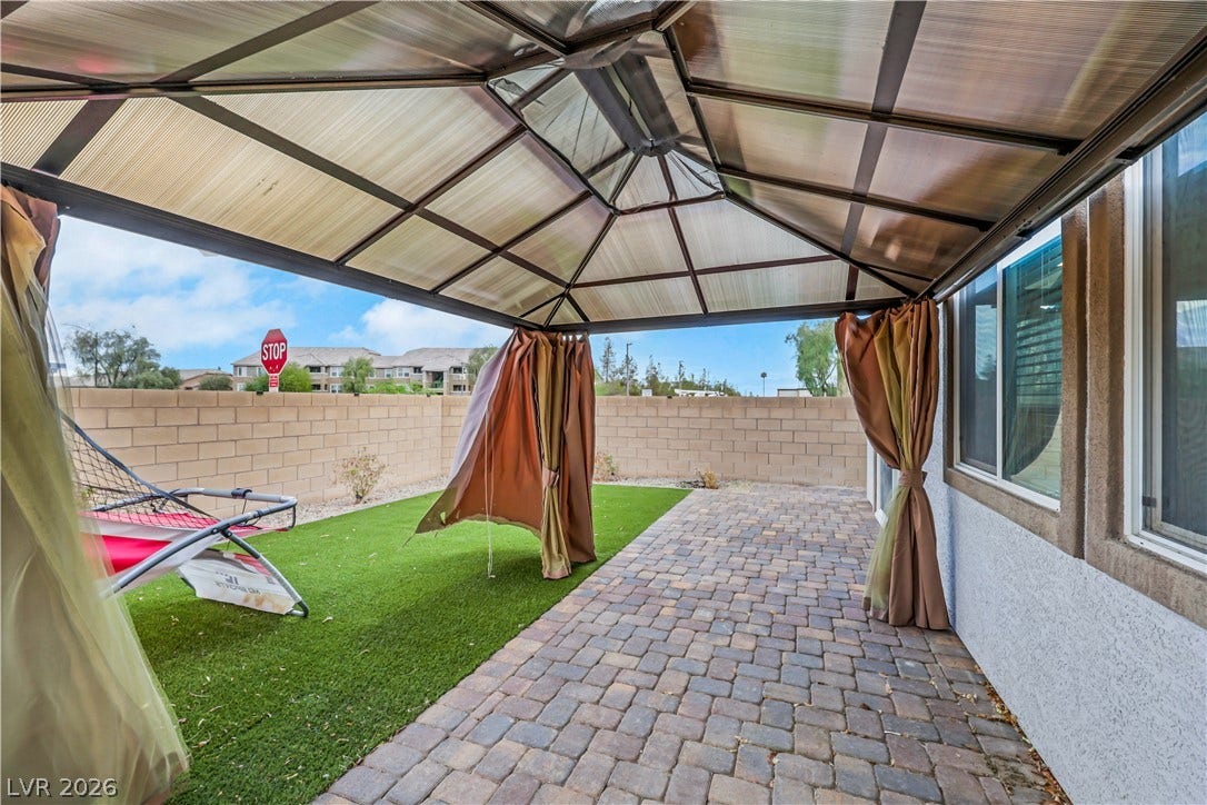 Sheltered pavilion provides shade over the brick paver patio and synthetic lawn.