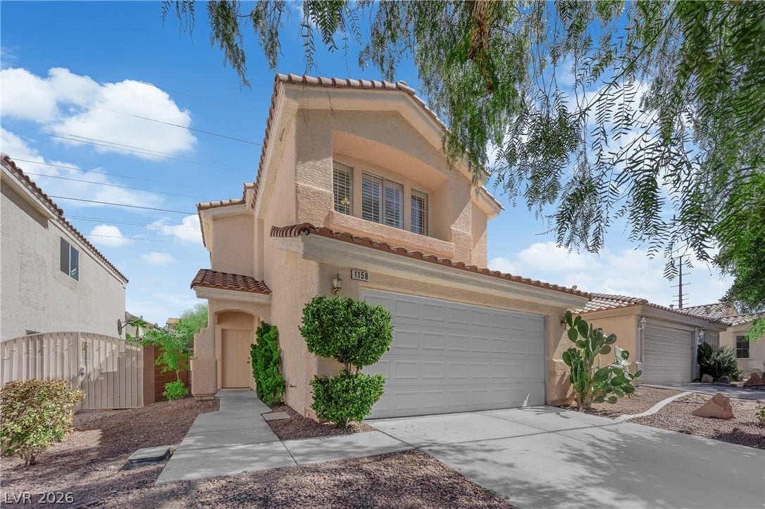 1158 Ekalaka Road, Henderson, NV 89052 Spanish tile rooflines and stucco siding define this two-story exterior framed by desert landscaping.