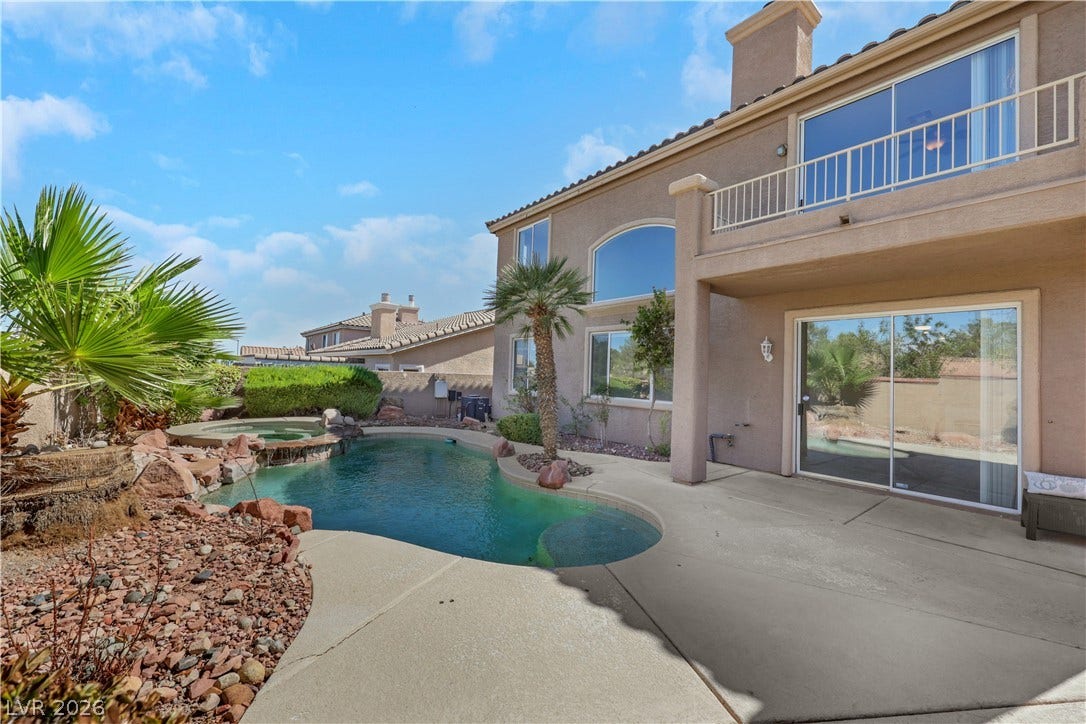 An inviting backyard oasis features a custom swimming pool alongside a classic stucco exterior.