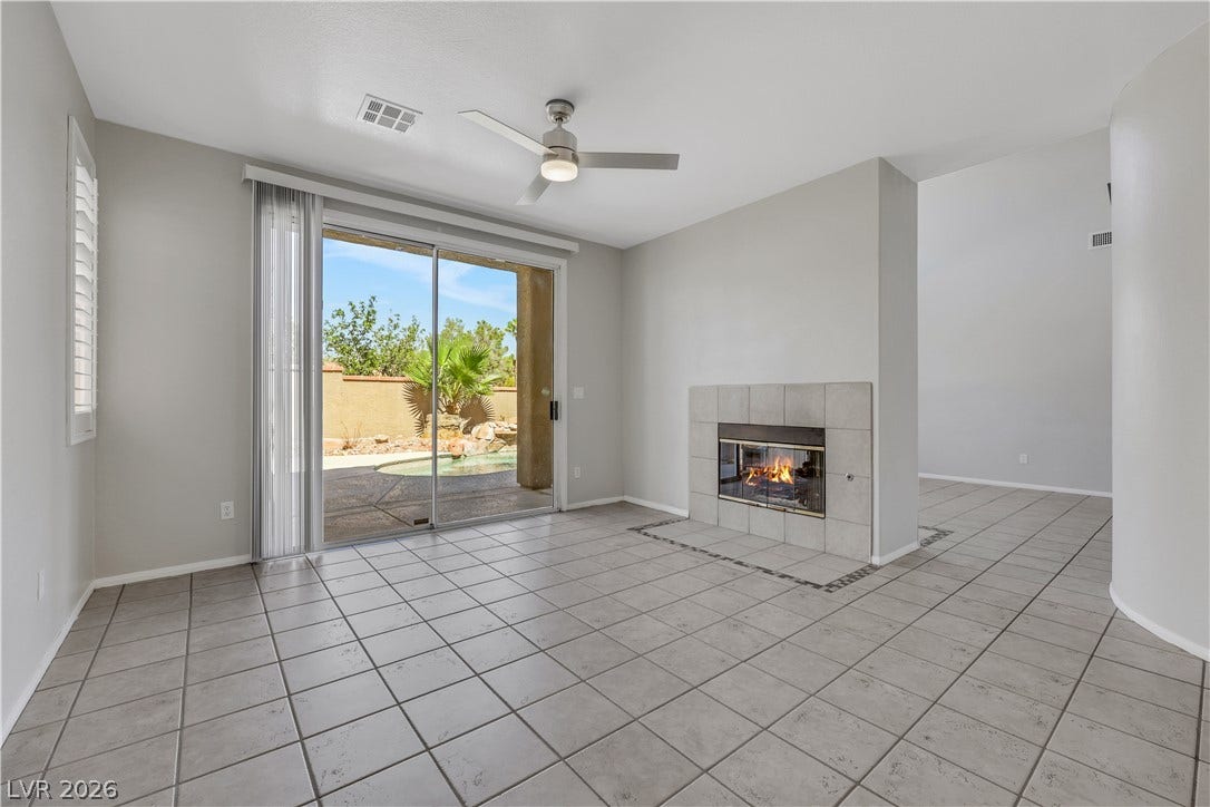 Tiled flooring anchors this open room featuring a tiled fireplace and sliding glass doors.