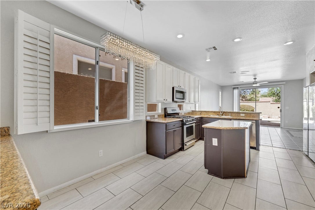 Tiled floors and granite countertops highlight this open kitchen design with an central island.