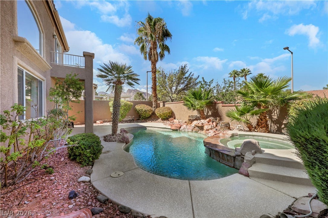 Mature palms and a stone-ringed spa surround this sparkling backyard swimming pool.
