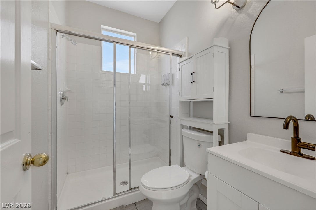 A glass-enclosed shower highlights this modern, neutral bathroom with a clean-lined vanity.