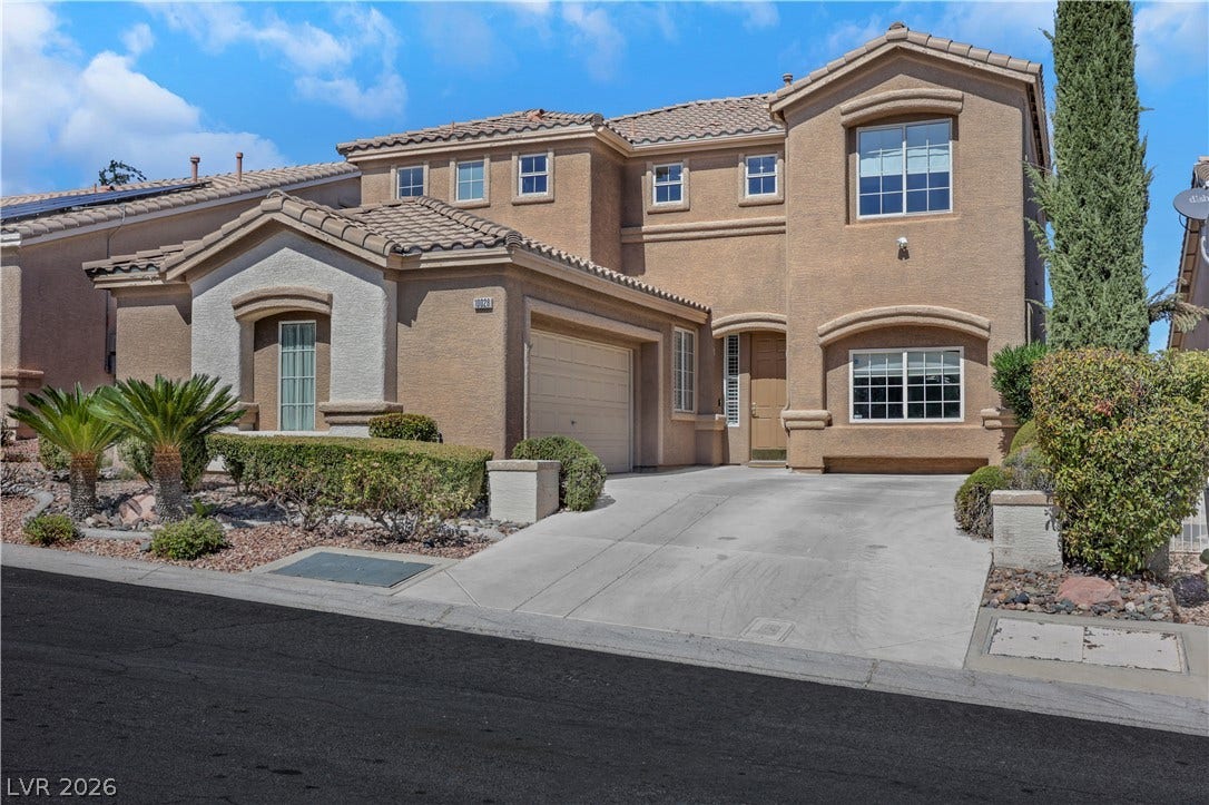 A spacious driveway leads to this classic stucco exterior featuring a tiled roof structure.