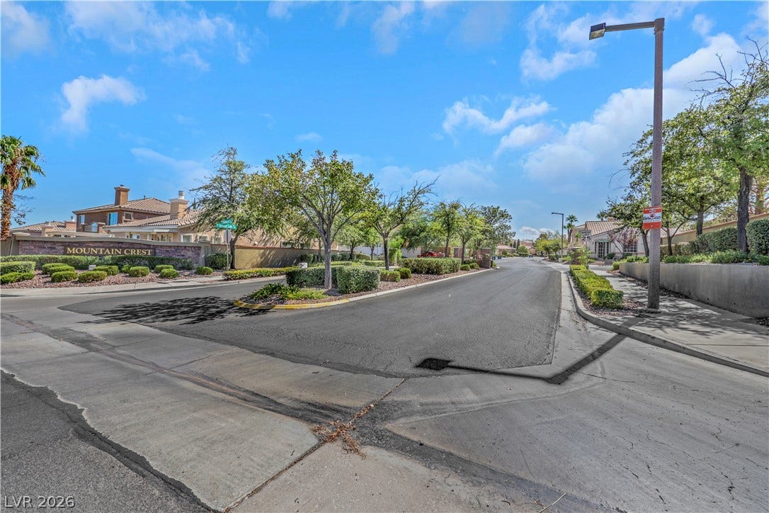 Manicured landscaping and paved sidewalks line the inviting entrance to this neighborhood.