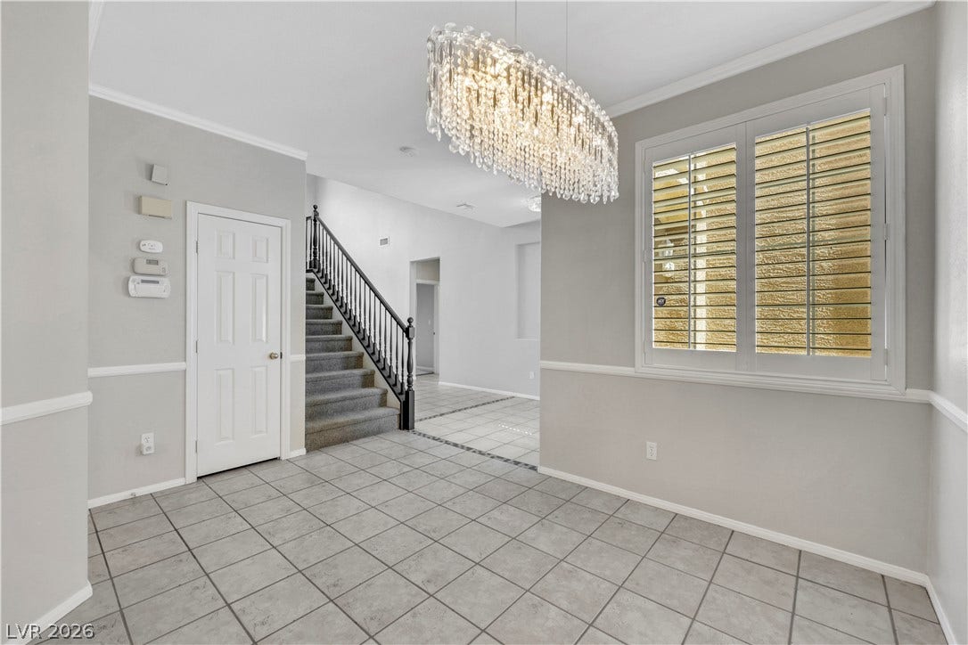 Tiled floors and elegant crown molding frame this inviting entry hall featuring plantation shutters.
