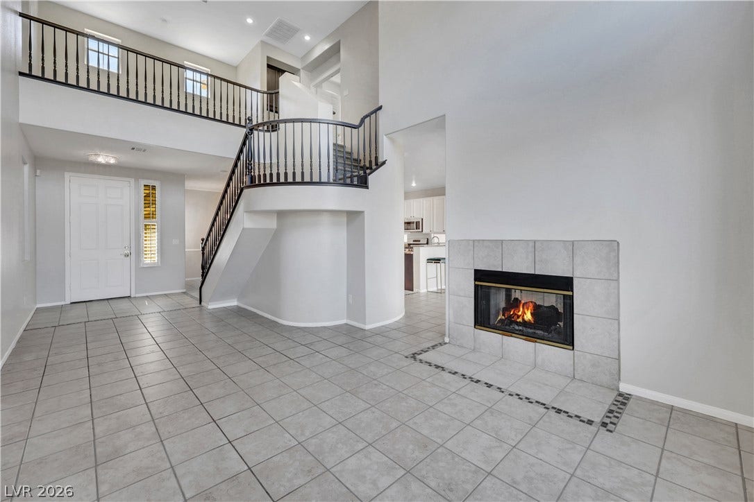 An inviting tiled hearth and a dramatic curved staircase anchor this soaring double-height living space.
