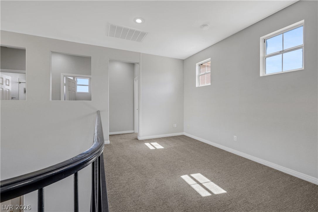 A versatile upper-level loft showcases clean architectural lines and soft carpeting underfoot.