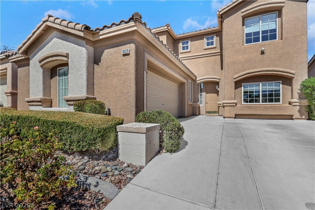 Stucco exterior elements and a concrete driveway lead to the recessed main entryway.