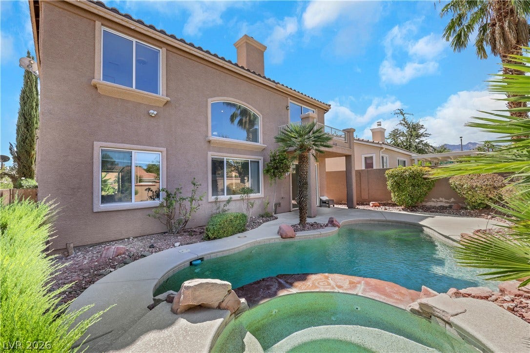 An inviting backyard oasis centers around a custom swimming pool and integrated spa.
