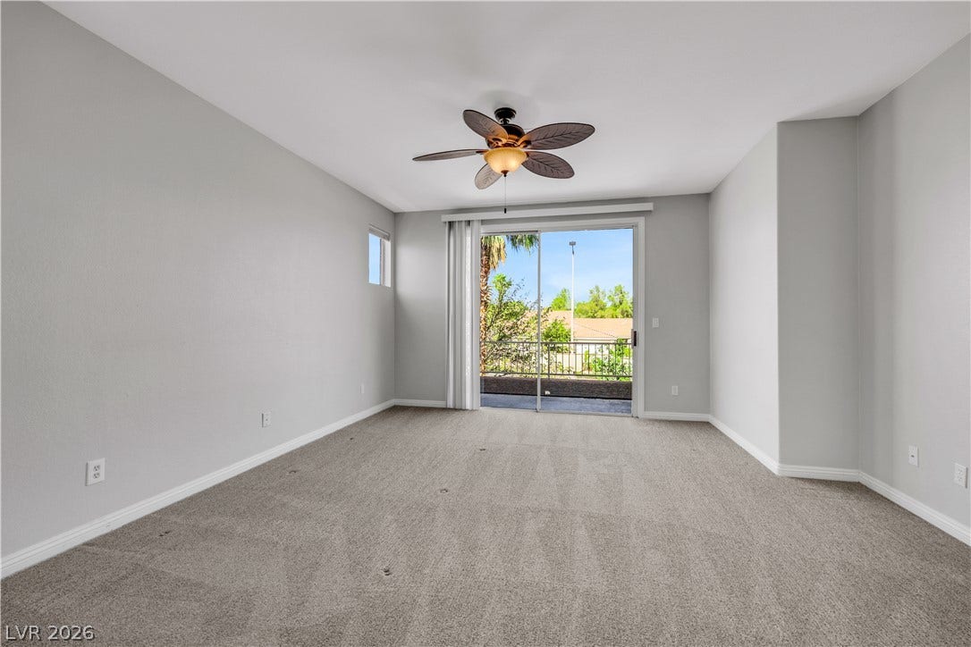 Sliding glass doors open from this carpeted bedroom to a private balcony space.
