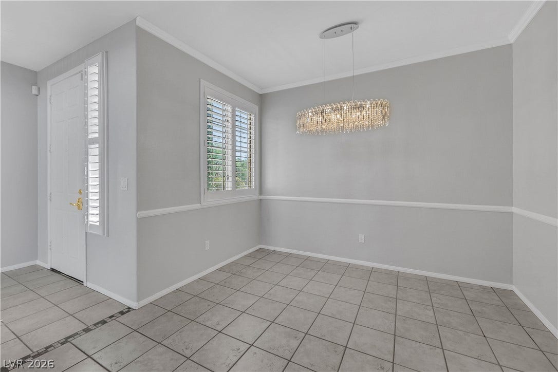 Tiled floors and elegant crown molding define this versatile dining area featuring plantation shutters.
