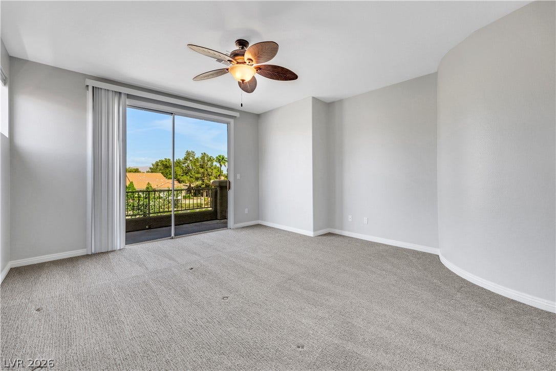 Sliding glass doors open directly to a private balcony overlooking green trees.