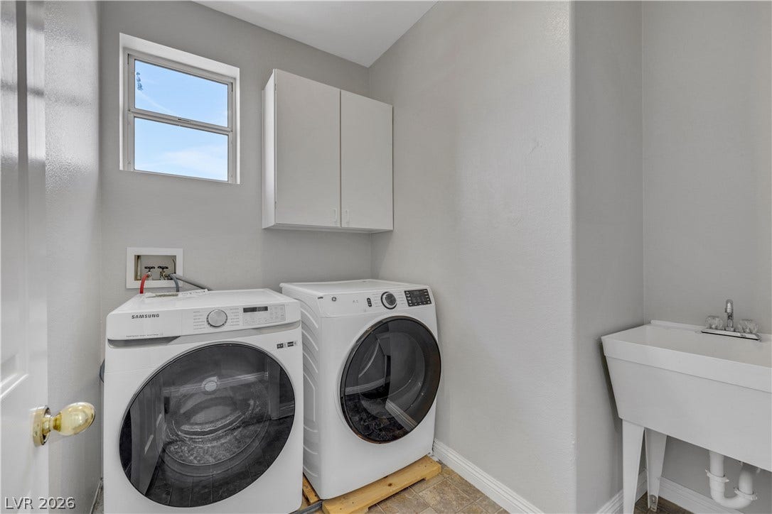 A functional laundry space highlights built-in upper cabinetry and a deep utility sink.