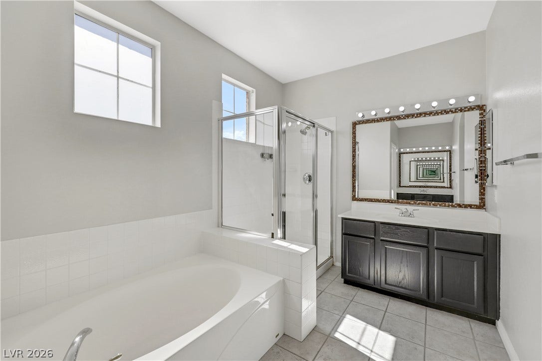 High ceilings and a glass-enclosed shower complement the tiled soaking tub in this bathroom.