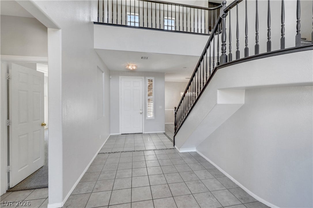 An airy entry foyer showcases durable tile flooring and a grand open staircase.