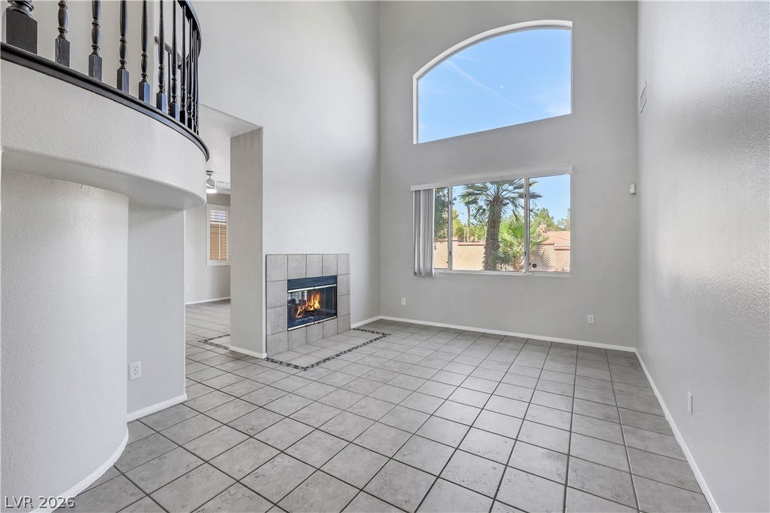 Towering ceilings and a tiled fireplace define this airy living space with curved upper balustrade.
