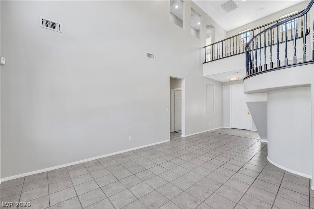 A soaring entry features clean-lined tile flooring and a curved second-story overlook.