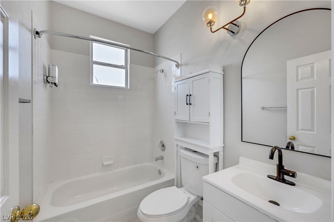 Clean lines and a functional layout define this bright bathroom with a tiled tub shower.