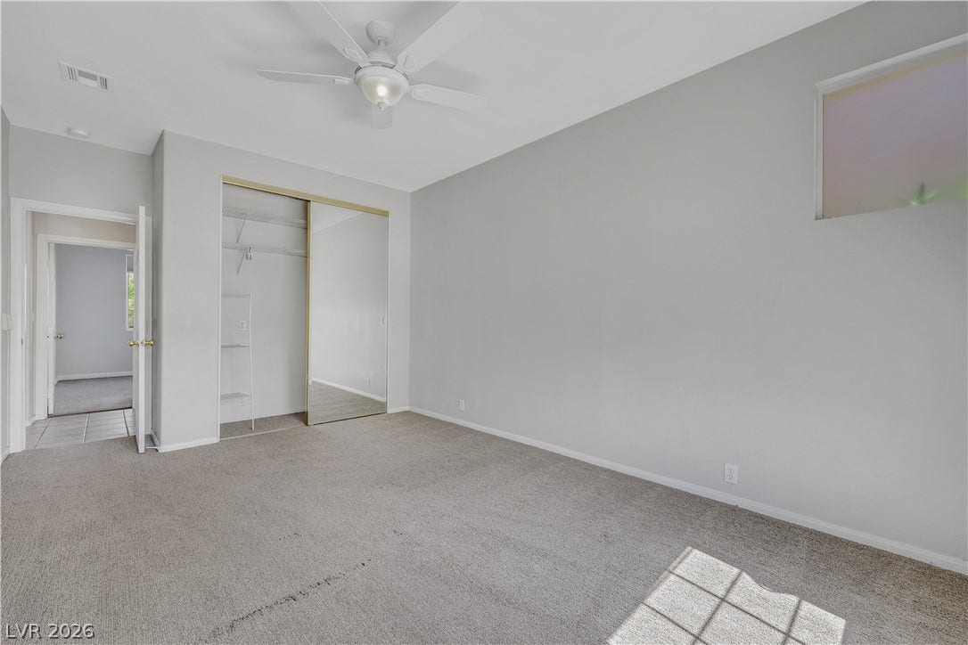 Soft carpeting underfoot and an inset high window create a peaceful bedroom atmosphere.