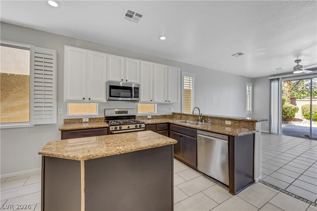 Polished stone countertops pair with clean cabinetry in this open-concept kitchen.