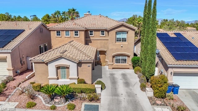 Mediterranean-inspired architecture defines this multi-level stucco home framed by neat landscaping and tile roofing.
