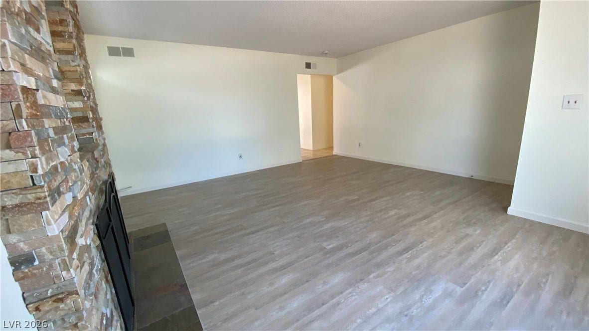 Las Vegas, NV 89119 A stone fireplace anchors this open room featuring durable wood-look flooring and clean neutral walls.