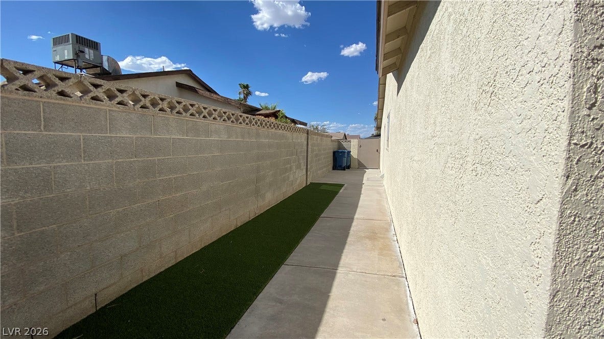 Las Vegas, NV 89119 A concrete walkway sits alongside textured stucco walls under clear blue skies.