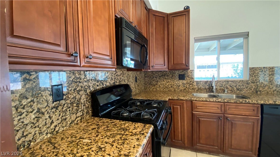 Las Vegas, NV 89119 Rich wood cabinetry surrounds granite countertops and integrated appliances in this functional workspace.