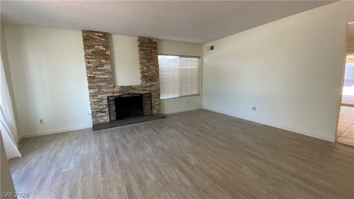 Las Vegas, NV 89119 Smooth wood-look flooring and a dual-pillar stone fireplace anchor this welcoming room.