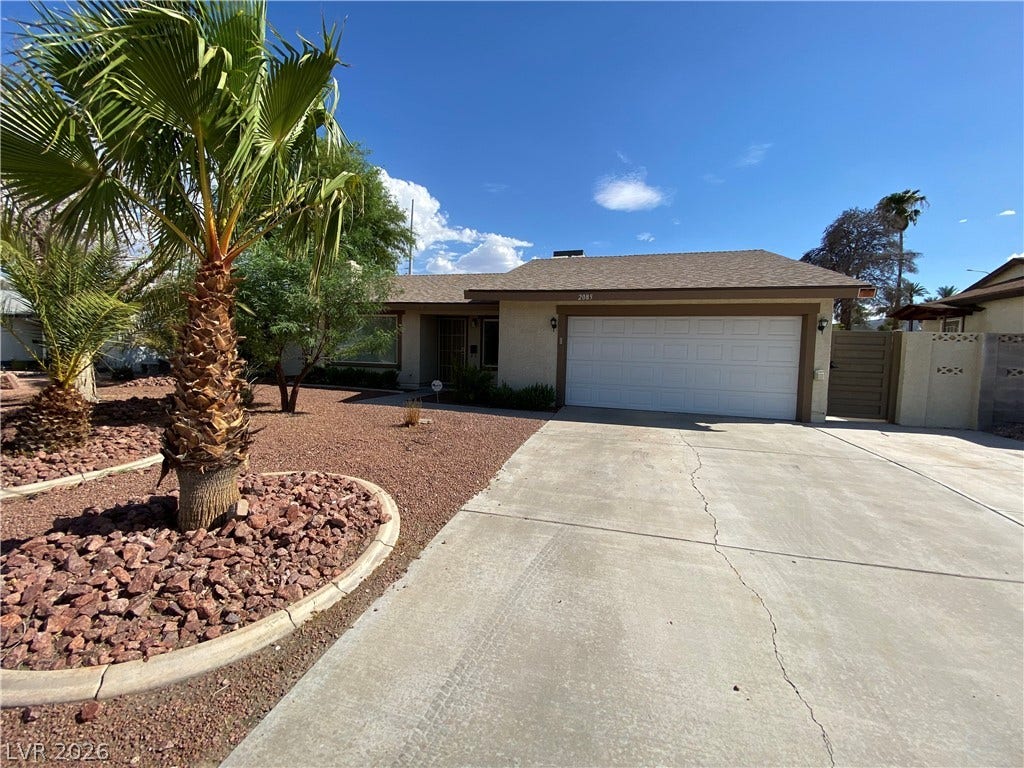 Las Vegas, NV 89119 Palm trees frame a concrete driveway leading to the attached garage of this single-story home.