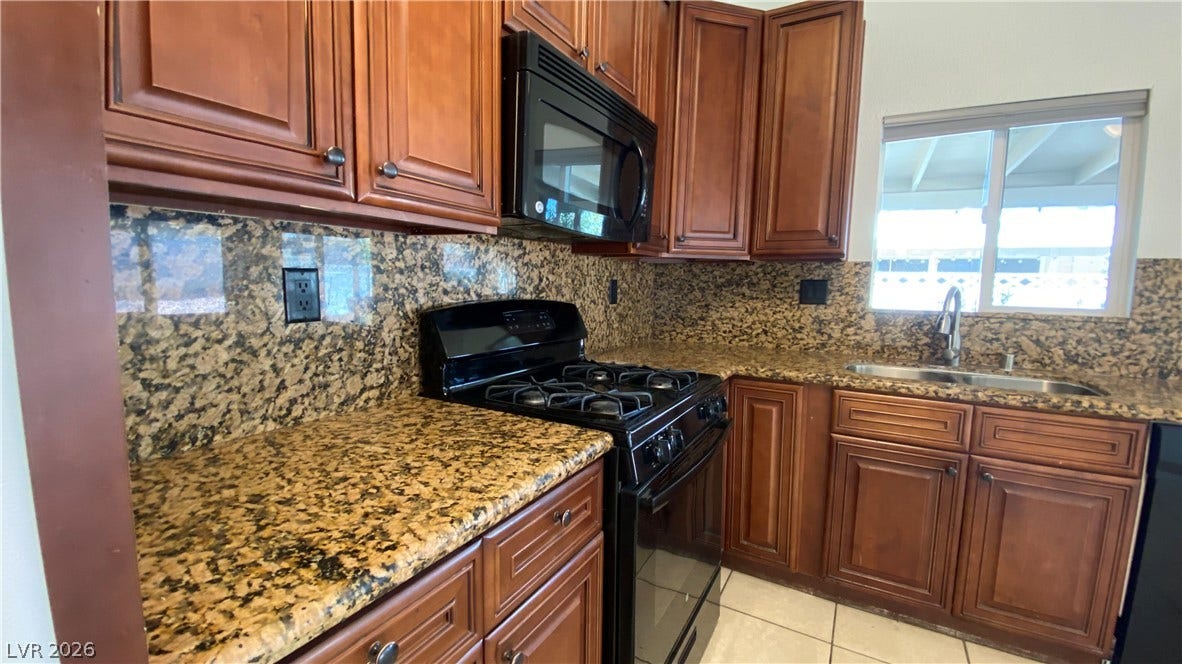 Las Vegas, NV 89119 Rich wood cabinets and polished granite countertops elevate this functional kitchen space.