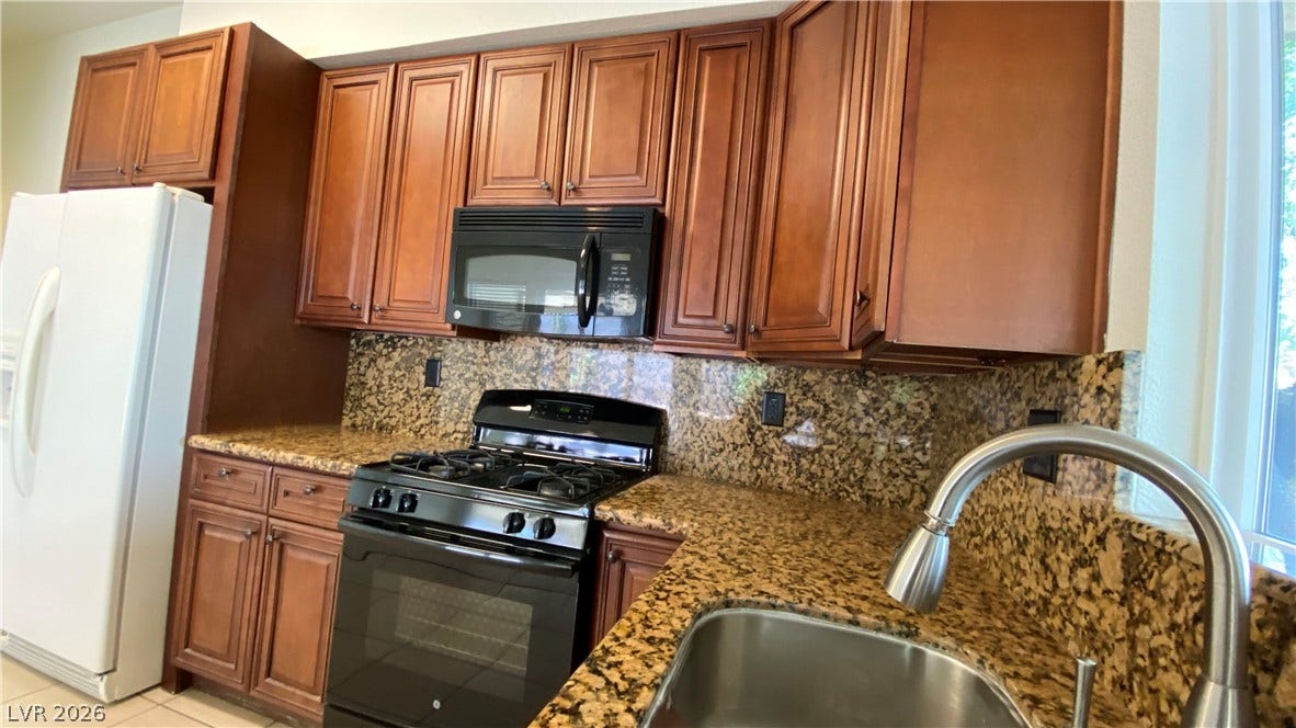 Las Vegas, NV 89119 Rich wood cabinetry surrounds integrated appliances and sleek granite countertops.