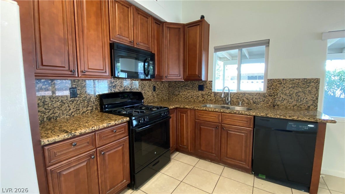 Las Vegas, NV 89119 Rich wood cabinetry surrounds granite countertops in this functional workspace featuring tile floors.