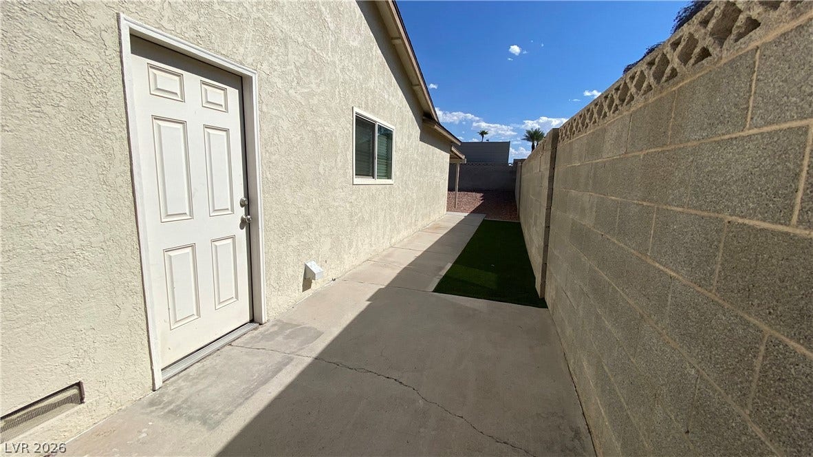 Las Vegas, NV 89119 A paved concrete walkway lines the side of this stucco home enclosed by block fencing.