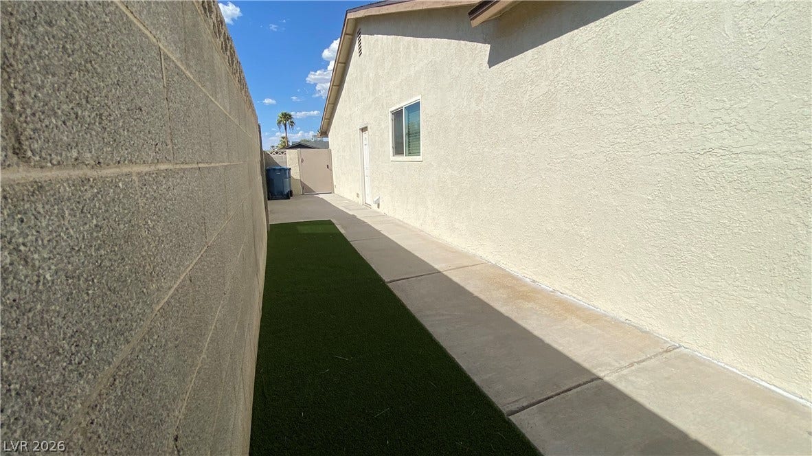 Las Vegas, NV 89119 A clean concrete walkway runs alongside the low-maintenance yard bordered by a sturdy block wall.