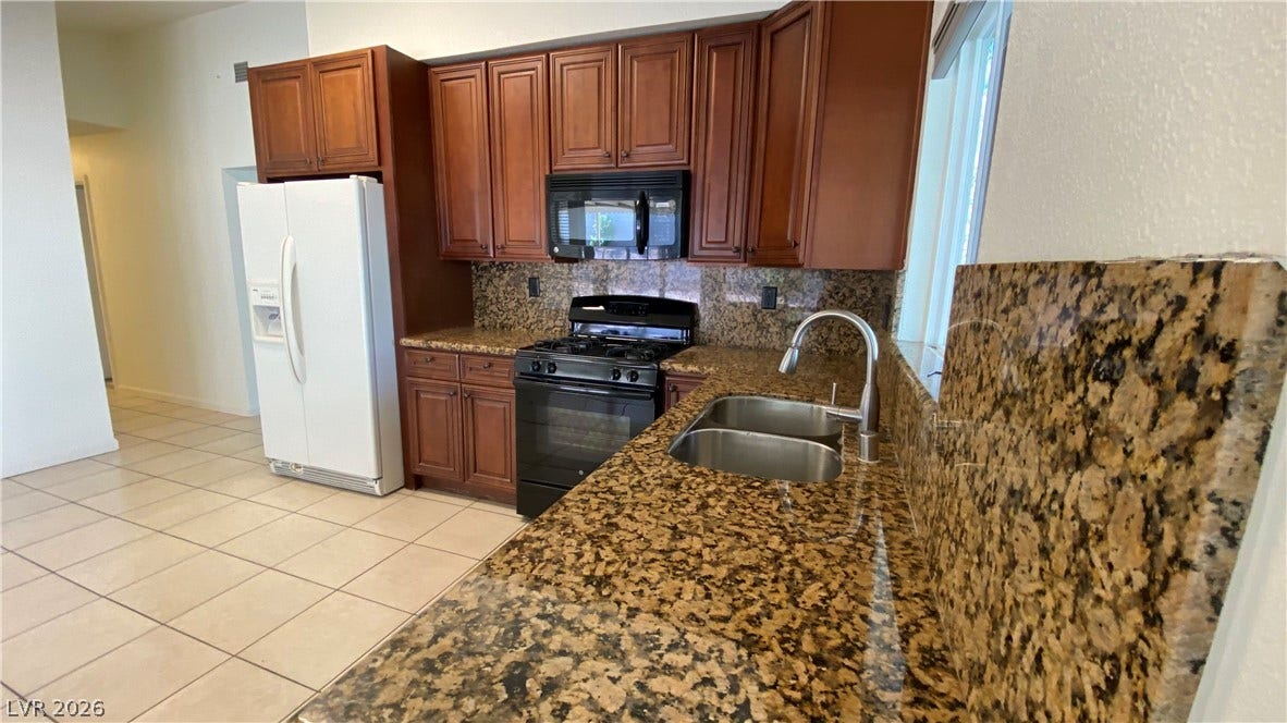 Las Vegas, NV 89119 Rich wood cabinetry paired with extensive granite countertops defines this functional cooking space.