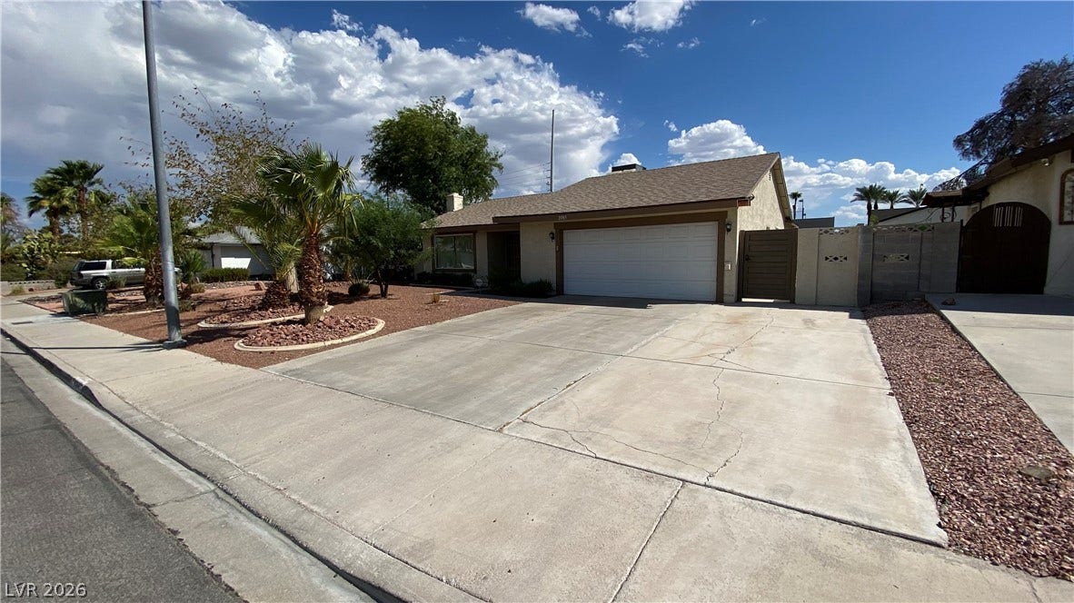 Las Vegas, NV 89119 An expansive concrete driveway leads to a two-car garage under a classic tiled roof line.