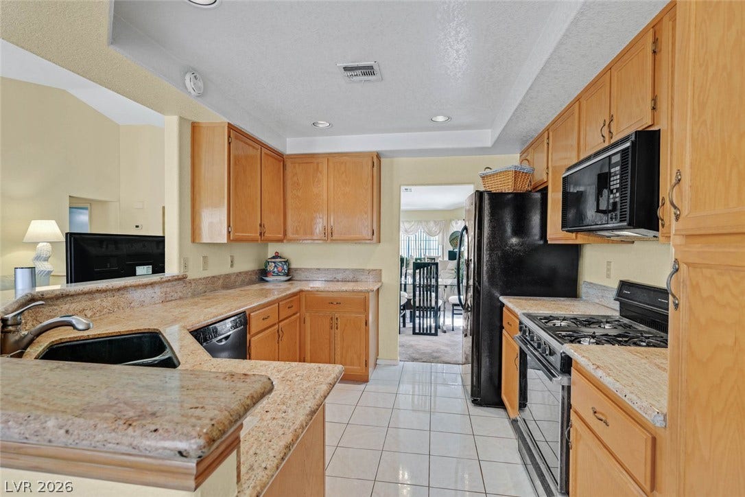 805 Stillwater Lane, Henderson, NV 89014 Gleaming tile floors complement classic wooden cabinetry and granite countertops in this functional workspace with breakfast bar