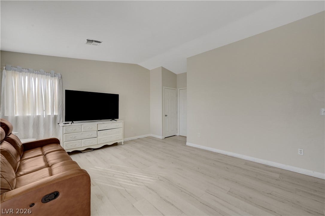 2025 Hollow Oak Avenue, North Las Vegas, NV 89031 Vaulted ceilings and wide-plank wood-style floors elevate this versatile living space.