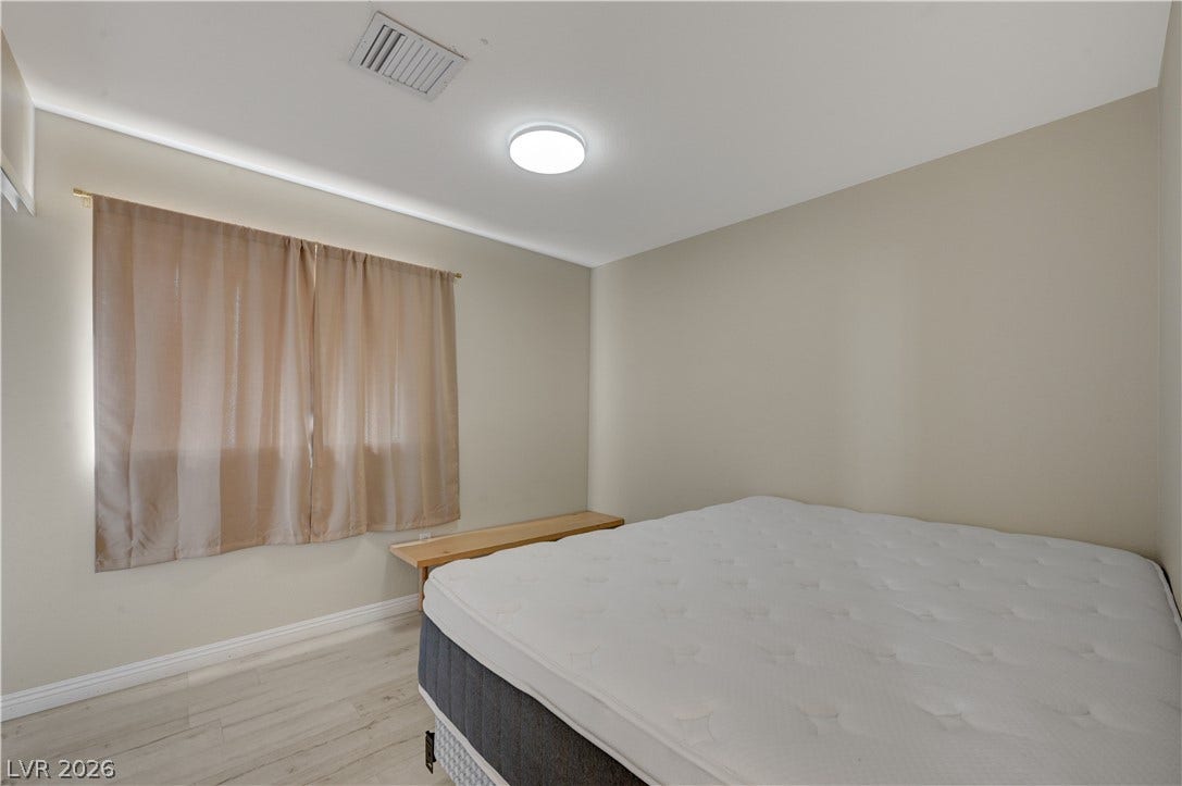 2025 Hollow Oak Avenue, North Las Vegas, NV 89031 Smooth wood flooring and a flush ceiling light fixture anchor this tranquil bedroom space.