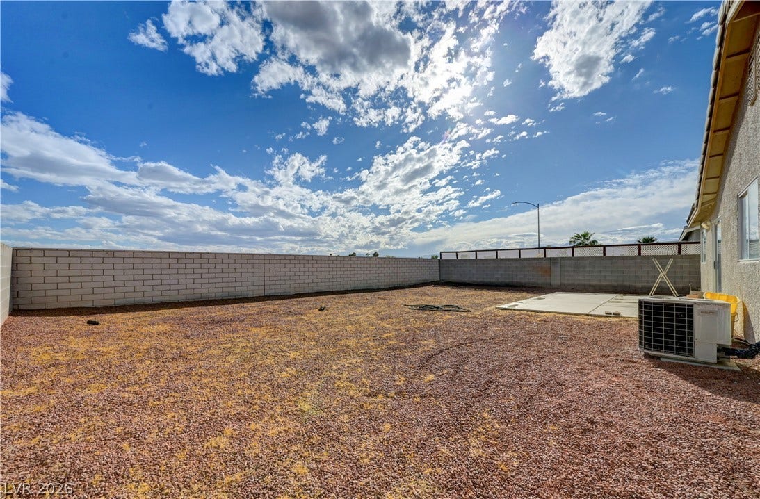 2025 Hollow Oak Avenue, North Las Vegas, NV 89031 An enclosed backyard features gravel ground cover alongside a concrete patio slab.