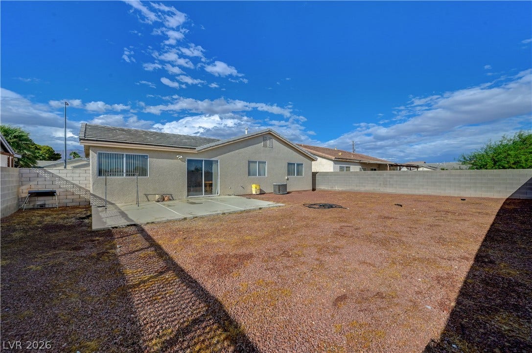 2025 Hollow Oak Avenue, North Las Vegas, NV 89031 A spacious backyard features a concrete patio and a secure block wall perimeter.