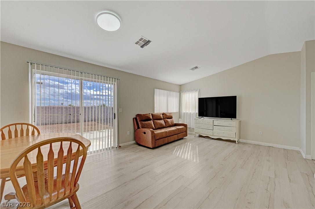 2025 Hollow Oak Avenue, North Las Vegas, NV 89031 Sliding glass doors open to the backyard from this airy living space with light wood-look flooring.