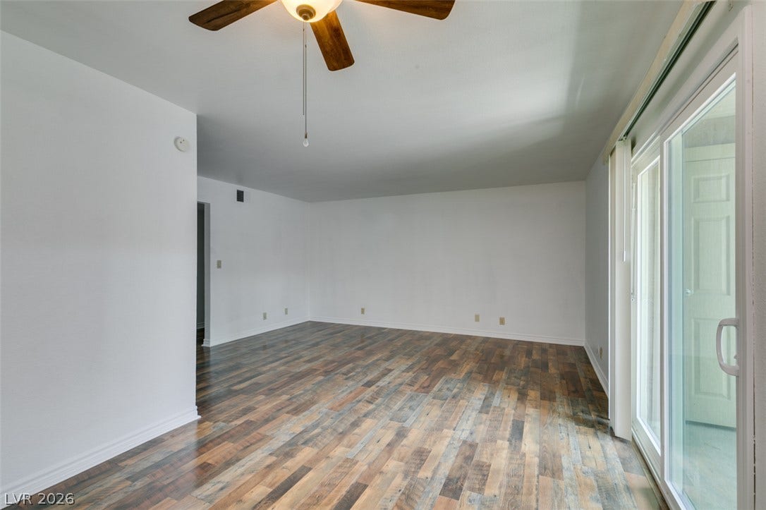 5240 Indian River Drive, #273, Las Vegas, NV 89103 Rich wood-look flooring stretches across the open living area toward large sliding glass doors.